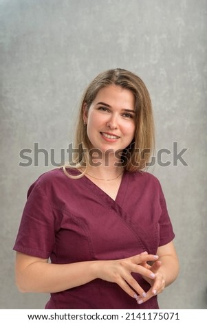 Portrait of young smiling female masseur in uniform. Attractive girl with natural appearance and long hair. Vertical frame
