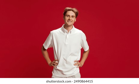 Portrait of young smiling guy, wearing white polo shirt, expressing positivity and confidence against red studio background. Concept of youth, human emotions, fashion, lifestyle - Powered by Shutterstock