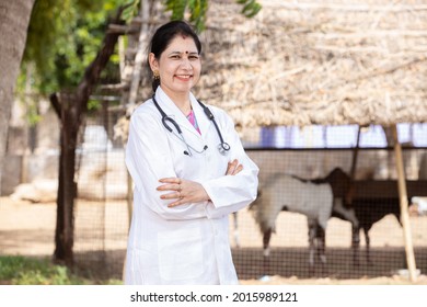 Portrait Of Young Smiling indian Female Doctor Wearing Stethoscope and Apron Standing Cross Arms At Village, She is looking at camera with positive emotions,  Rural healthcare and medical concept. 