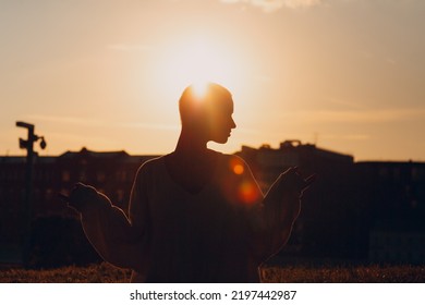 Portrait Of Young Smiling Millenial European Short Haired Woman Silhouette Doing Yoga Lotus Asana On Green Grass Meadow Summer Park. Beautiful Happy Blonde Girl Outdoor.