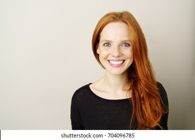 Portrait Of Young Smiling Red-haired Woman Against Plain Background