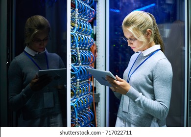 Portrait of young smiling woman checking data on digital tablet while working with supercomputer in research center - Powered by Shutterstock