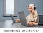 portrait a young smiling woman in hijab wears headset using laptop,working in call center service,talking with client,concept of telemarketing,customer relationship management(CRM)