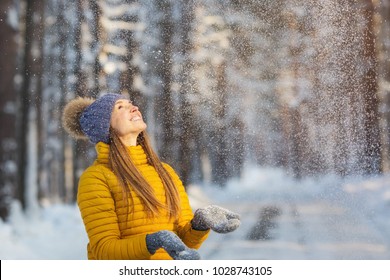 Portrait Of Young Smiling Woman Looking To Falling Snow In A Winter Forest