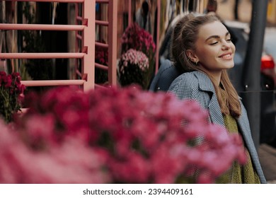 Portrait of young smiling woman near flower bouquets at florist store on city street. Customer, buyer. Saleswoman. Woman florist. Small business. Floral shop. - Shutterstock ID 2394409161