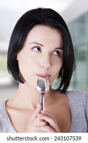 Portrait Of Young Smiling Woman With Spoon In Her Mouth