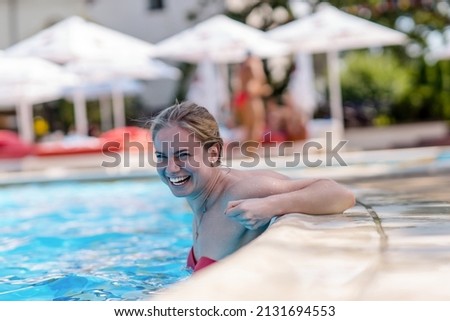 Portrait of a young smiling woman in the swimming pool.Pretty girl resting on the edge of a swimming pool.Sexy girl relaxing in water on hot sunny day.
