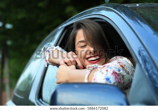 Portrait\
of a young and smiling woman traveling in a\
car.
