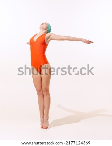 Portrait of young sportive woman in swimming suit and cap preparing to jump into the pool isolated on grey background . Concept of beauty, fashion, vintage style, summertime, party. Copy space for ad