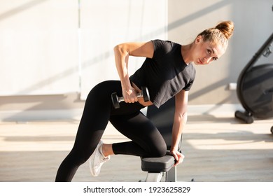 Portrait young sports woman lifting dumbbell in gym