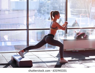 Portrait of young sporty girl doing stretching exercise near large window