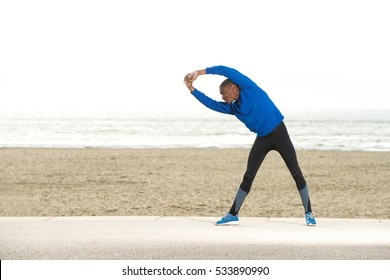 Portrait of young sporty guy stretching exercise at the beach - Powered by Shutterstock