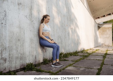 Portrait of young sporty woman in sportswear excercising in front of concrete wall in the city. - Powered by Shutterstock