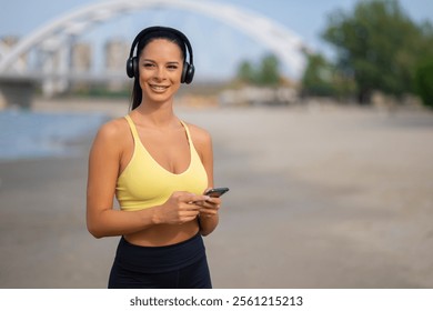 Portrait of young sporty woman using phone to select music for workout - Powered by Shutterstock