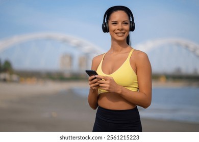 Portrait of young sporty woman using phone to select music for workout - Powered by Shutterstock