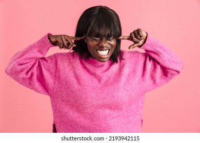 Portrait of young stressed african woman pushing on her temples with fingers with closed eyes and clenched teeth while standing over isolated pink background - Shutterstock ID 2193942115