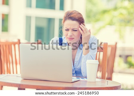 Portrait young stressed displeased worried business woman sitting in front of laptop computer isolated outdoors city background. Negative face expression emotion feelings problem perception