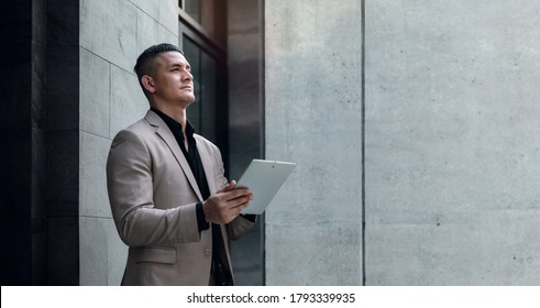 Portrait Of A Young Striving CEO Or Leader Working On Tablet.  Businessman Standing At The City And Looking Away