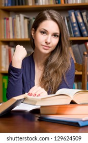 Portrait Of Young Student Studying Among Lot Of Books.