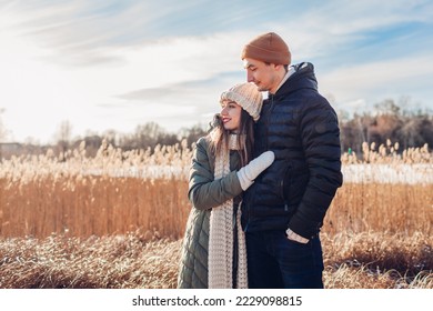 Portrait of young stylish loving couple walking by winter river. Man and woman hugging enjoying snowy landscape outdoors