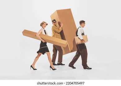 Portrait Of Young Stylish People Carrying Giant Cardboard Boxes Isolated Over White Background. Black Friday Shopping, Sales, Moving. Concept Of Retro Fashion, Style, Youth Culture, Emotions, Ad