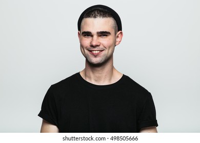 Portrait of young stylish toothy smiling man looking at camera. Studio shot.