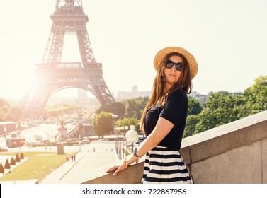 Portrait Of Young Stylish Woman In Hat Near The Eiffel Tower In Paris On Sunny Day