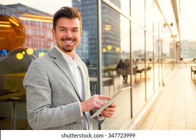 Portrait of a young successful businessman on background of office center