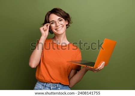 Portrait of young successful businesswoman hold netbook touching eyeglasses when deciding new project isolated on khaki color background