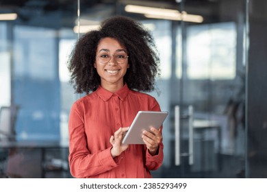 Portrait young successful businesswoman with tablet computer in hands inside office at workplace, female programmer testing new software smiling looking at camera satisfied with achievement results. - Powered by Shutterstock