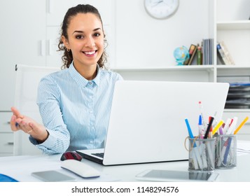 Portrait of young successful businesswoman working on laptop in modern office