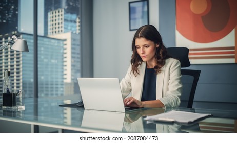 Portrait of Young Successful Caucasian Businesswoman Sitting at Desk Working on Laptop Computer in City Office. Ambitious Corporate Manager Plan Investment Strategy for e-Commerce Project.