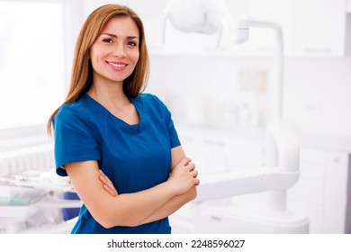 Portrait of young successful confident female doctor wearing uniform standing in ER and smiling with hands crossed - Powered by Shutterstock