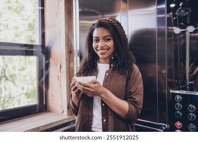 Portrait of young successful woman hold coffee cup elevator modern interior office business center indoors - Powered by Shutterstock