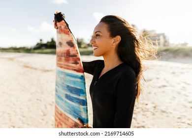 Portrait Of Young Surfer Woman On The Beach Holding Her Surfboard