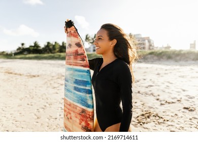 Portrait Of Young Surfer Woman On The Beach Holding Her Surfboard