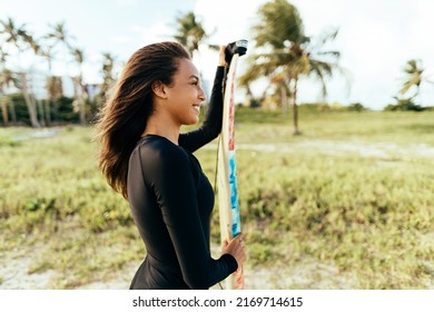 Portrait Of Young Surfer Woman On The Beach Holding Her Surfboard