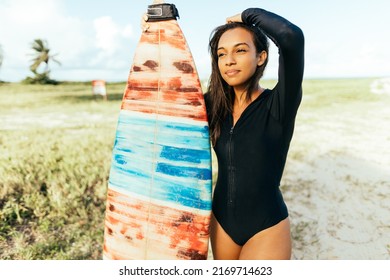 Portrait Of Young Surfer Woman On The Beach Holding Her Surfboard