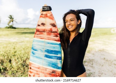 Portrait Of Young Surfer Woman On The Beach Holding Her Surfboard