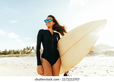 Portrait Of Young Surfer Woman On The Beach Holding Her Surfboard