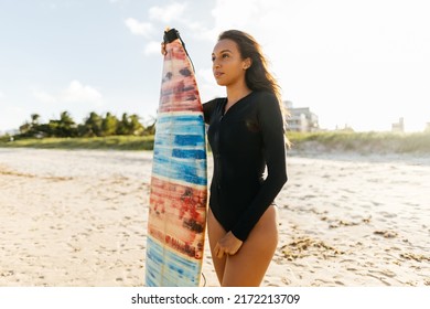 Portrait Of Young Surfer Woman On The Beach Holding Her Surfboard