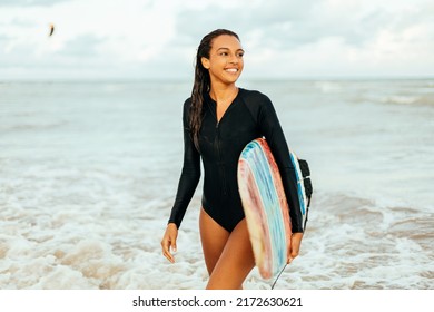 Portrait of young surfer woman on the beach holding her surfboard - Powered by Shutterstock