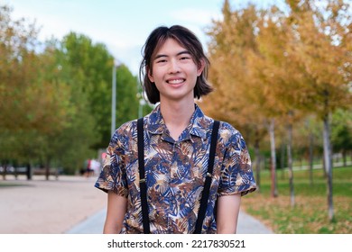 Portrait Of A Young Taiwanese Man Smiling And Looking At Camera In A Park.