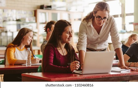 Portrait Of Young Teacher Helping A Student During Class. University Student Being Helped By Female Lecturer During Class.