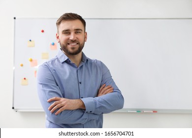 Portrait of young teacher near whiteboard in classroom
