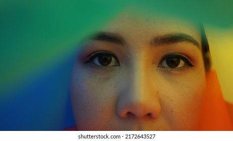 Portrait Young Teen Queer Transgender Asia People Look At Camera Under Colorful Stripes Flag. Closeup Eye Face Cry Sad Hiding True Self Identity In Gay LGBT LGBTQIA Bisexual Mental Illness Problem. 