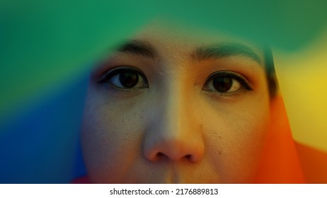 Portrait Young Teen Queer Transgender Asia People Look At Camera Under Colorful Stripes Flag. Closeup Eye Face Cry Sad Hiding True Self Identity In Gay LGBT LGBTQIA Bisexual Mental Illness Problem. 