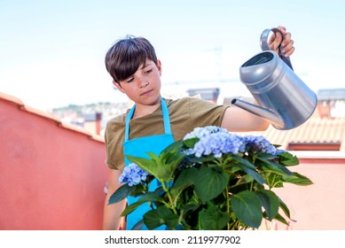 Portrait of young teen watering green plants on the balcony, small cozy garden in apartment