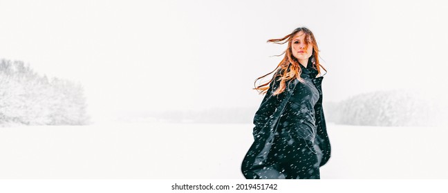 Portrait Of Young Teenage Girl With Long Hair In Black Coat On Natural Snow Background In Field. Winter Outdoor Photo