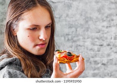 portrait of young teenager brunette girl with long hair eating slice of pizza on gray wall background - Shutterstock ID 1195931950
